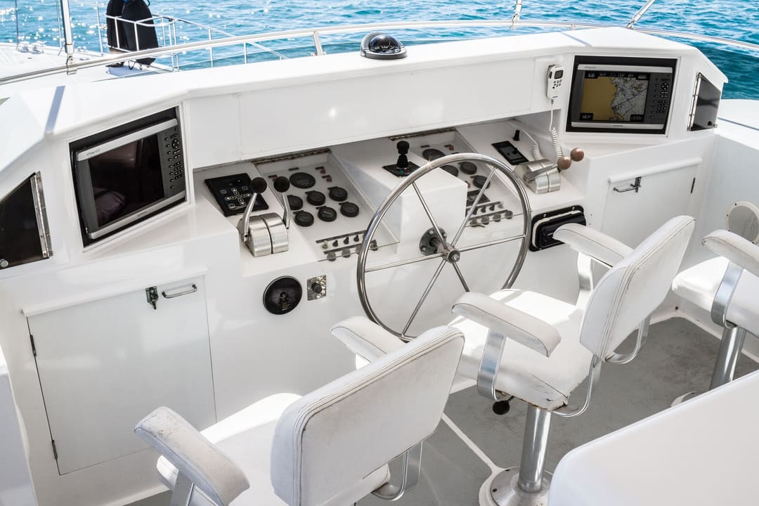 Puesto de mando de un yate con plotter, timón y butacas.